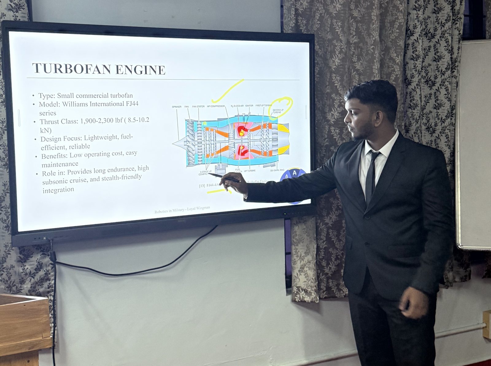 Dino Davis in a suit presenting a slide on a turbofan engine