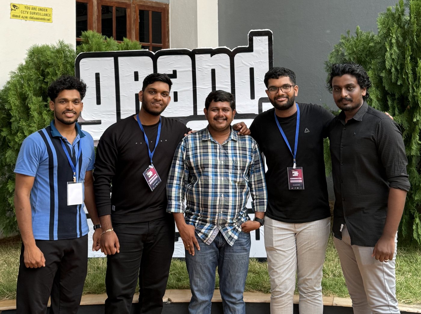 Five mentors standing in front of the Grand Tech Arena sign at Naipunnya Business School