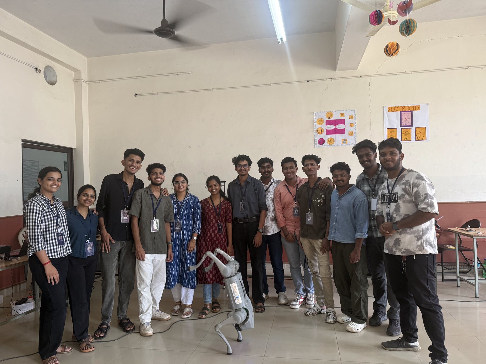 A group of students standing behind a quadruped robot in a classroom