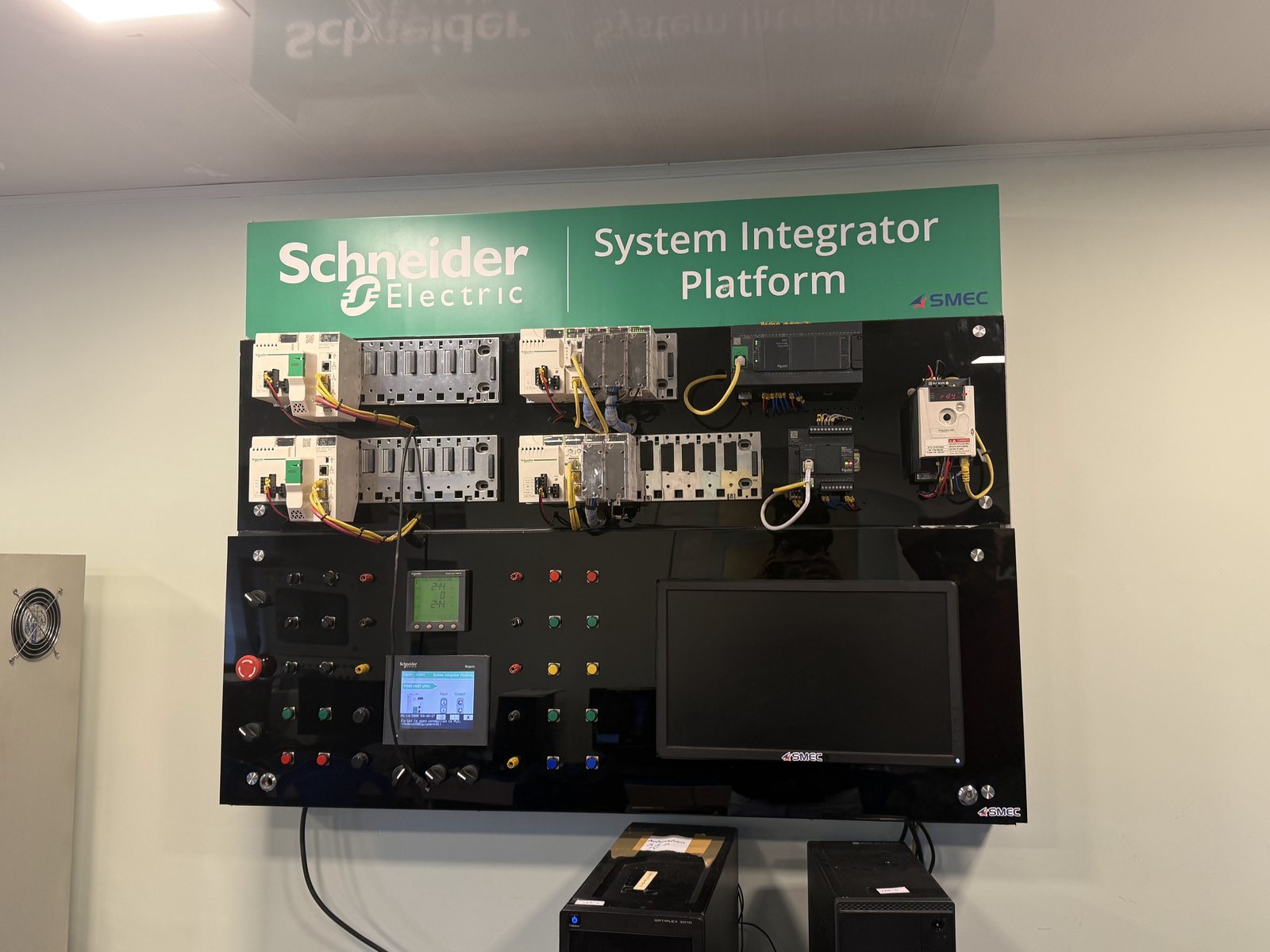 A Schneider Electric system integrator training platform with PLCs and an HMI